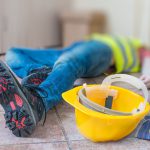 Leg and yellow helmet of injured lying worker at work.