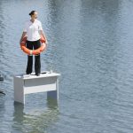 Businesswoman standing on desk with flotation device