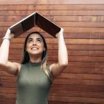 young brazilian woman holding laptop over head