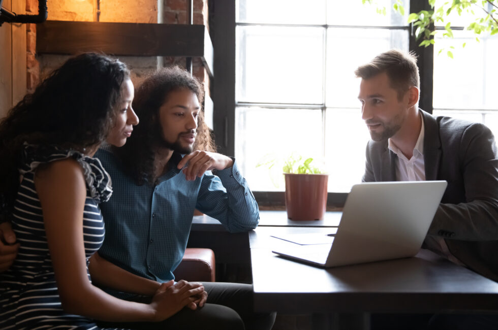 A mortgage broker discusses finance options with a young couple.