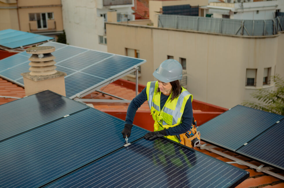 Electrician engineer installing solar energy panels on city residential rooftop.