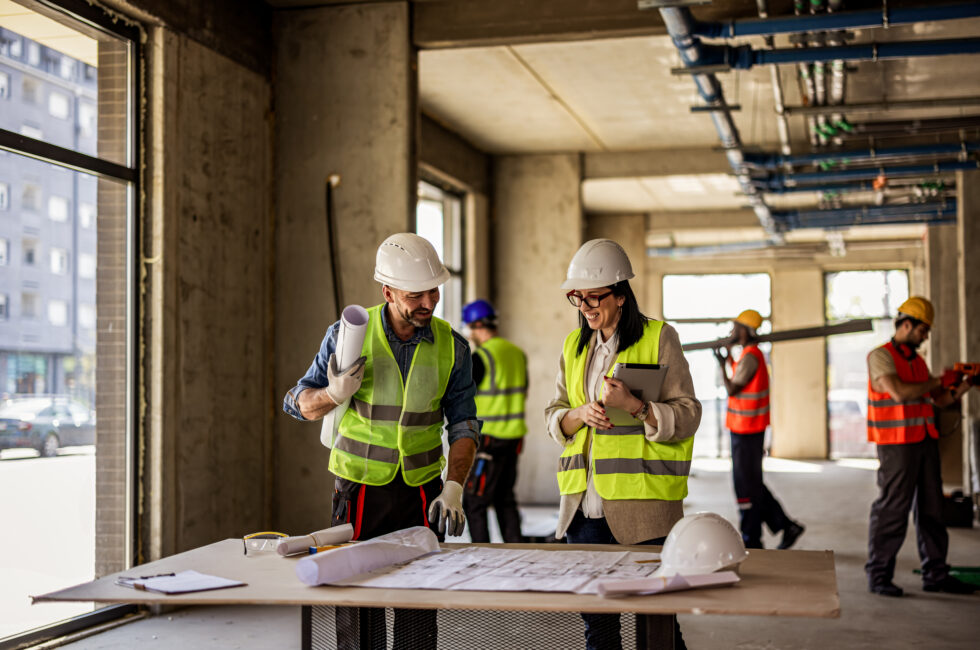 Two professionals on a building site are discussing plans.
