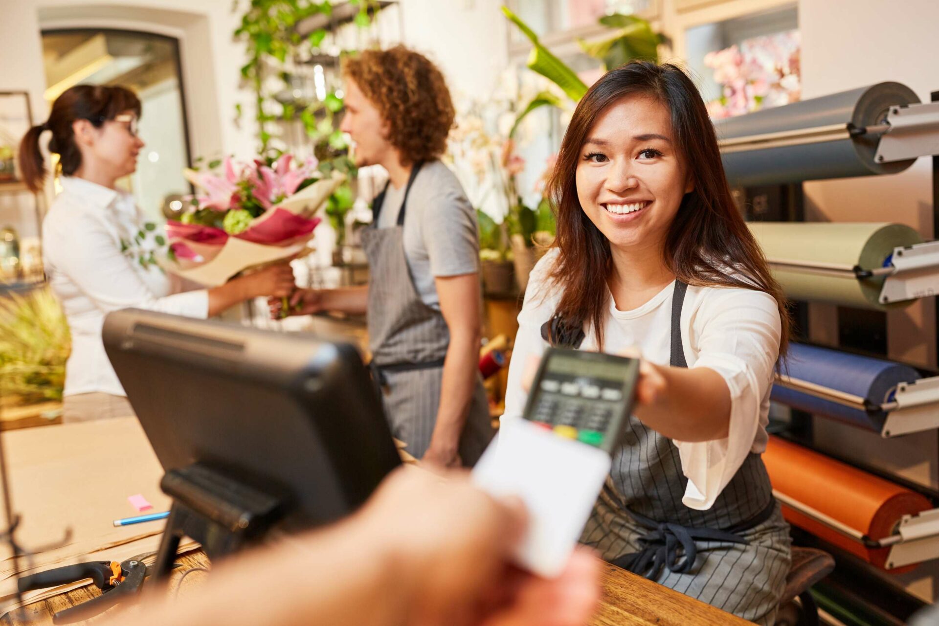 Young woman cashier takes credit card to pay at checkout