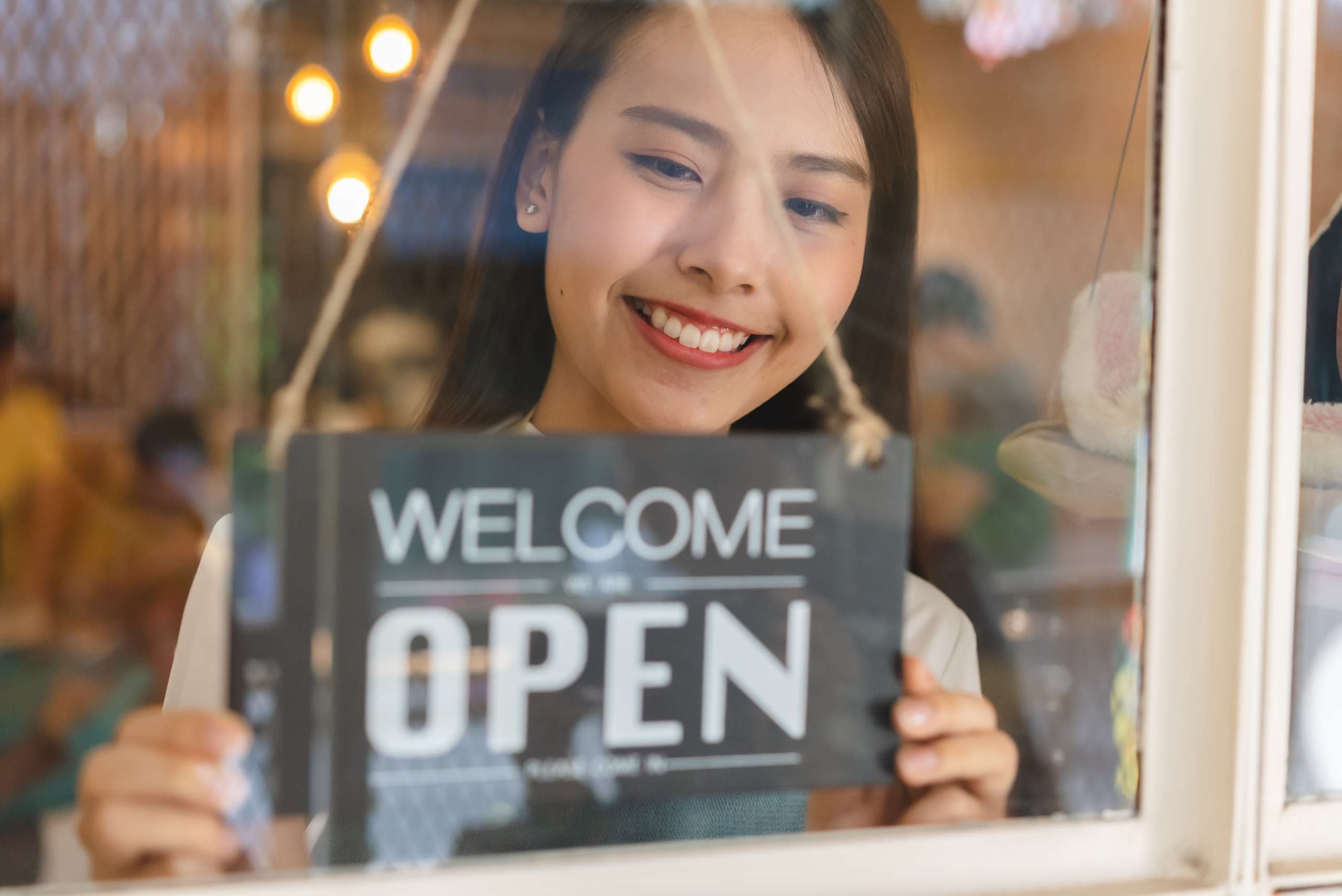 Female business owner with open sign at the door