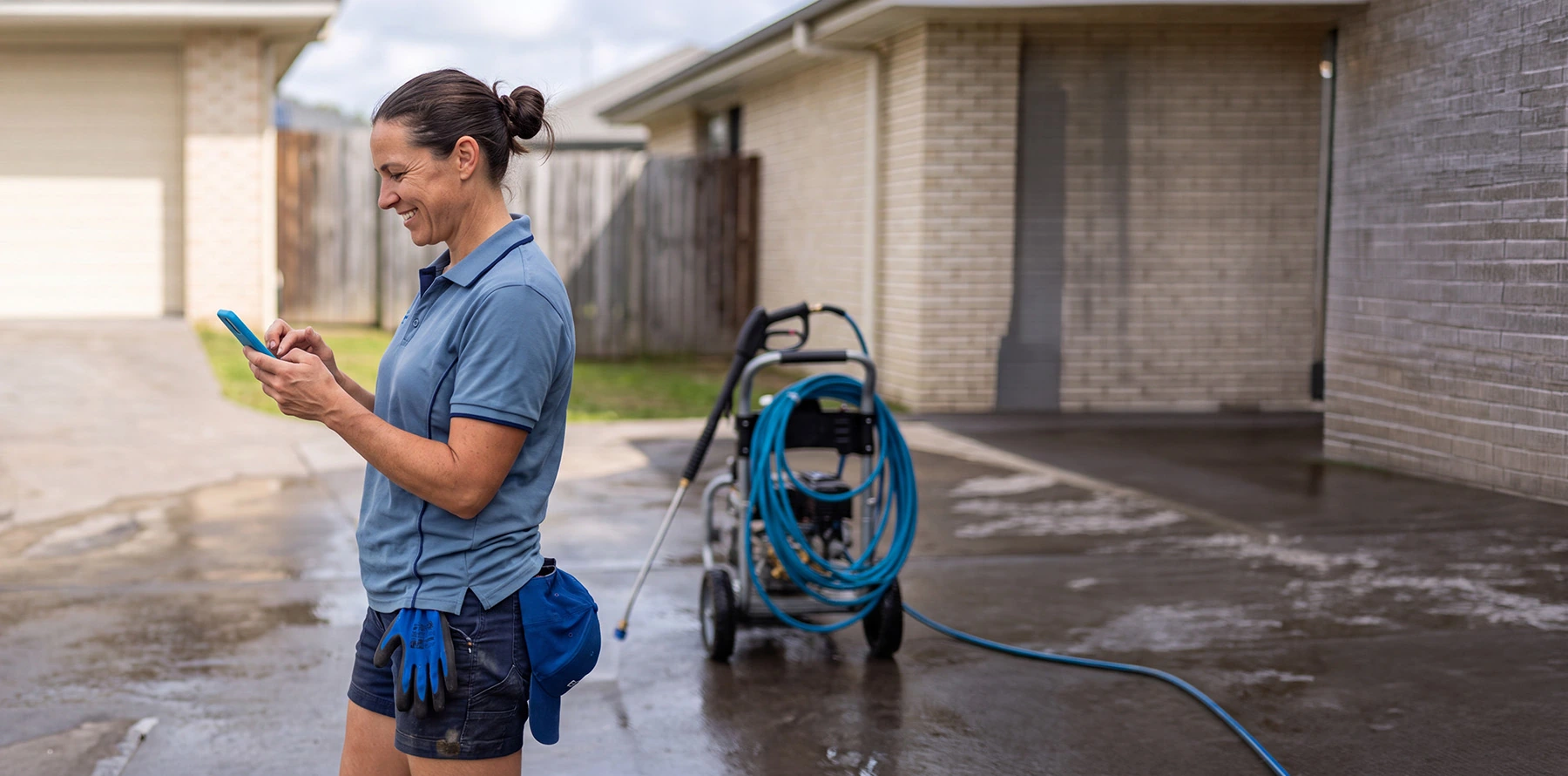 A happy pressure wash cleaner working on a job site with pressure wash machine