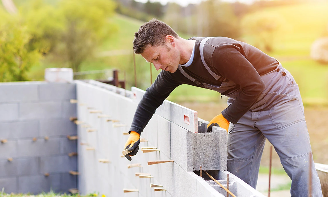 A bricklayer laying stone block on the wall 