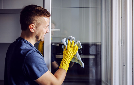 A cleaner in gloves cleans a glass door